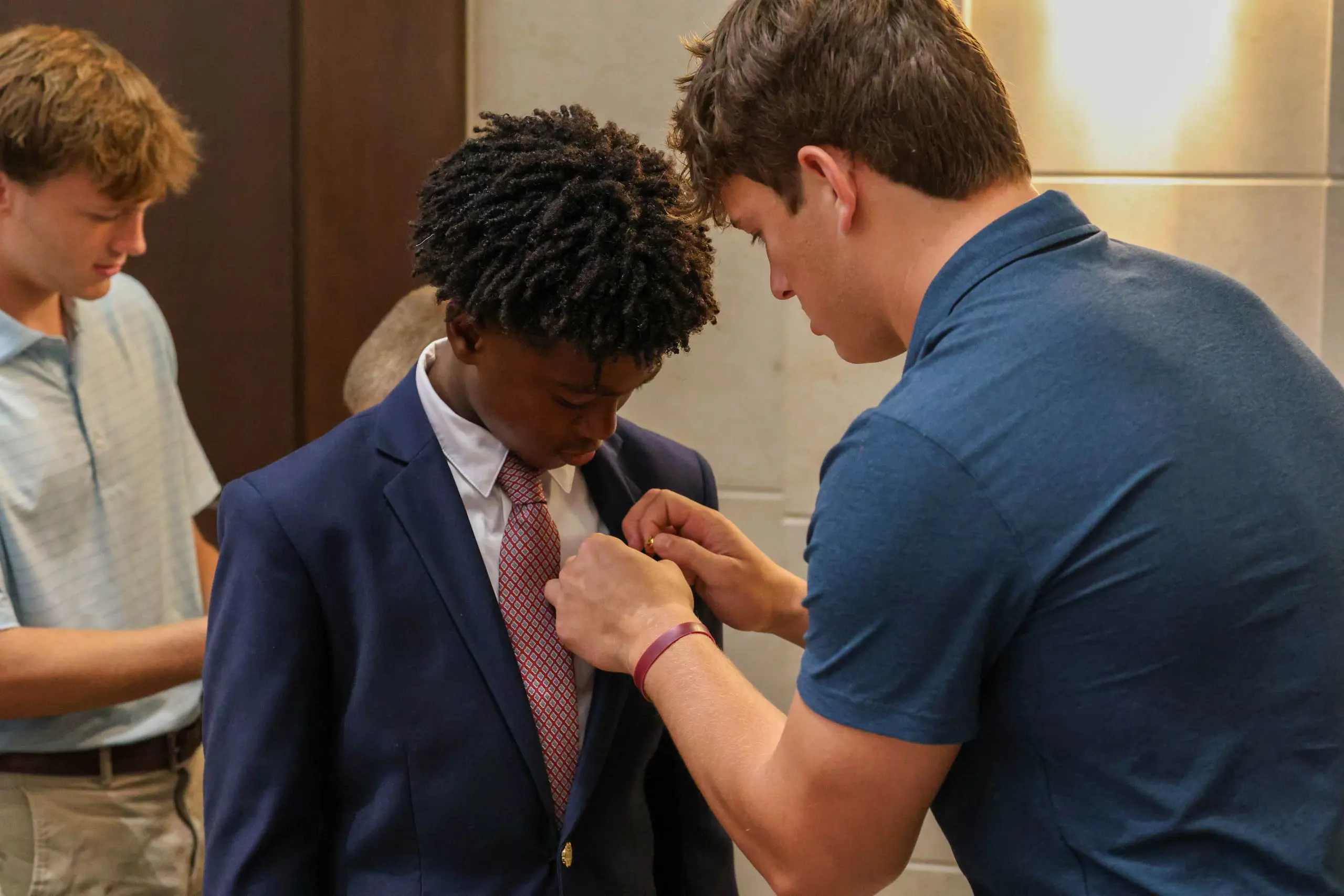Staff putting badge on student uniform