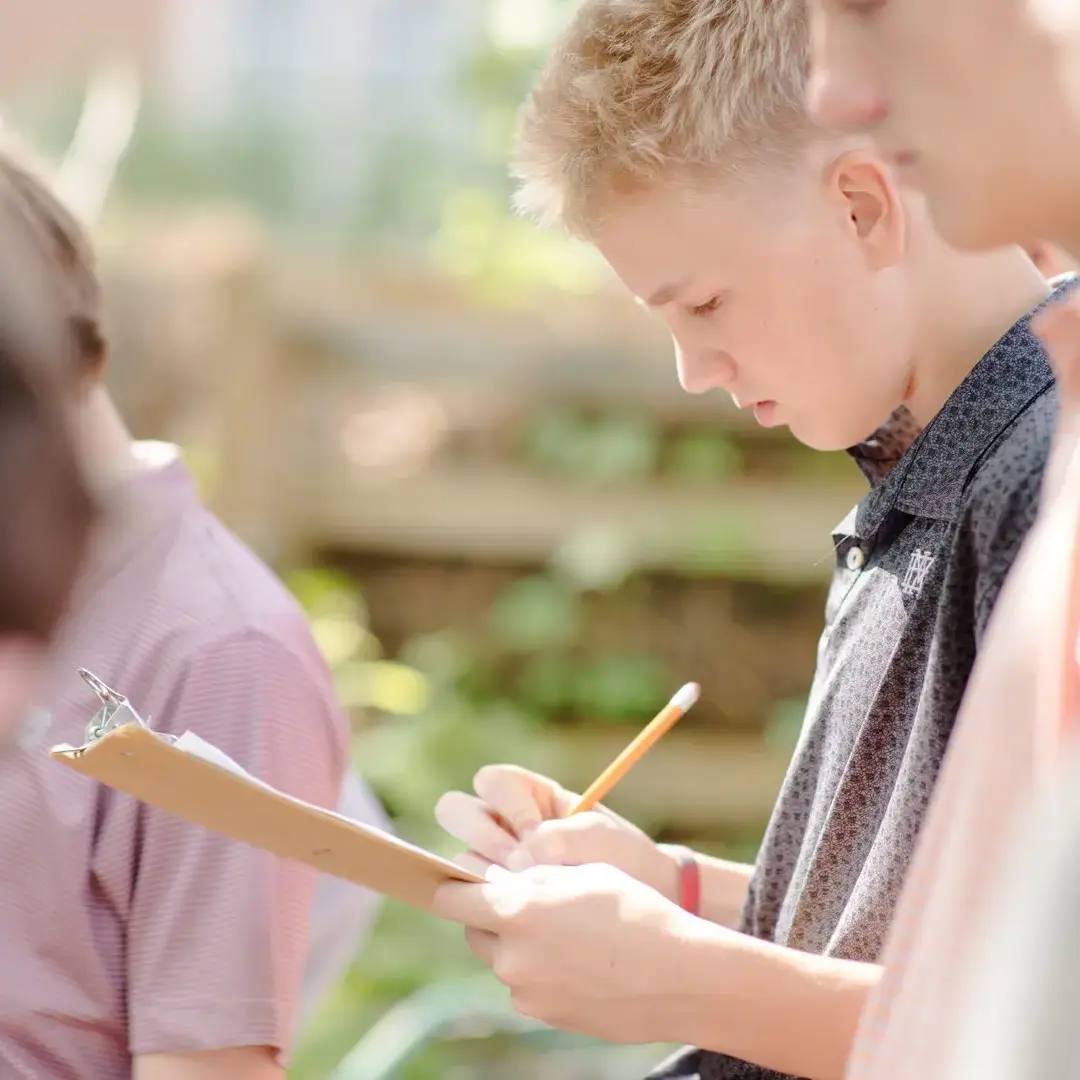 Young student writing notes outside
